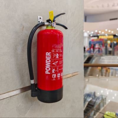 A powder fire extinguisher mounted on a wall inside a supermarket